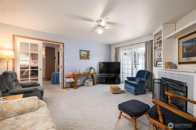 living area featuring carpet, a fireplace, and a ceiling fan