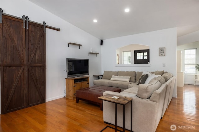 living room featuring a barn door, baseboards, lofted ceiling, light wood-type flooring, and recessed lighting