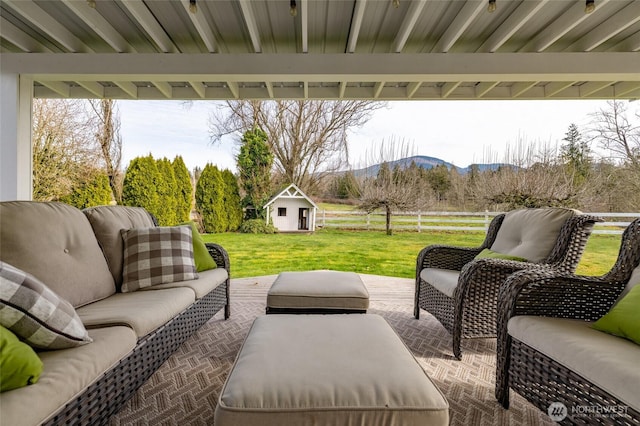 view of patio featuring an outdoor hangout area, an outdoor structure, fence, and a mountain view