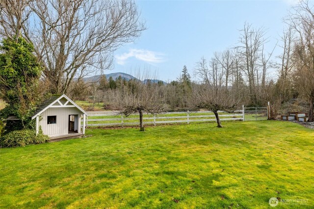 view of yard with an outbuilding, a rural view, fence, and a mountain view