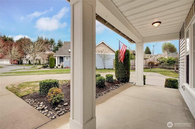 view of patio with a residential view, covered porch, and fence