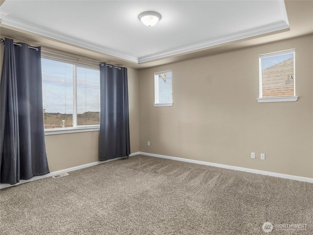 carpeted spare room featuring baseboards, visible vents, a tray ceiling, and ornamental molding