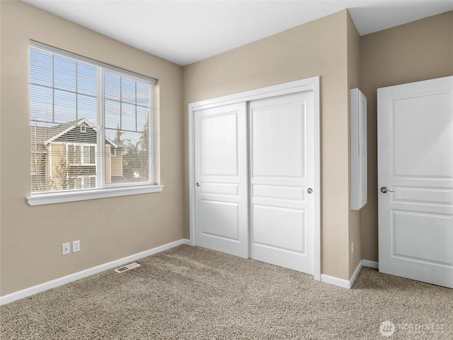 unfurnished bedroom featuring baseboards, a closet, visible vents, and carpet flooring