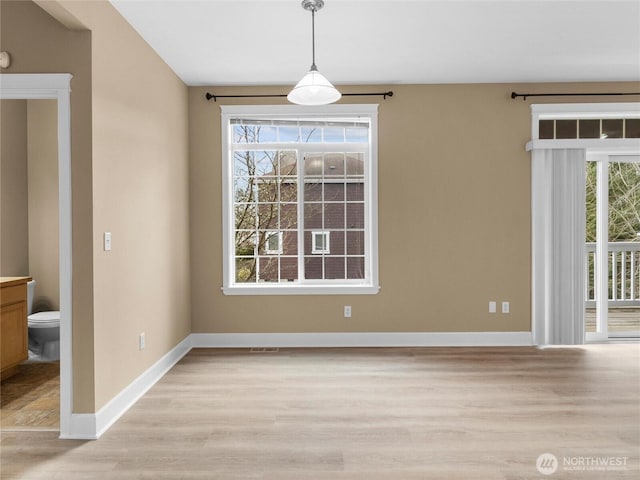 unfurnished dining area with light wood-style floors and baseboards