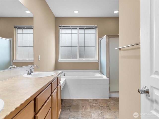 bathroom featuring a bath, a stall shower, double vanity, and a sink