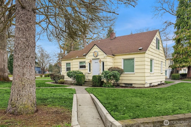 view of front facade with roof with shingles, a chimney, and a front yard