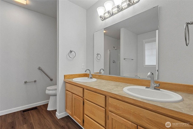 full bath with toilet, wood finished floors, a sink, and visible vents