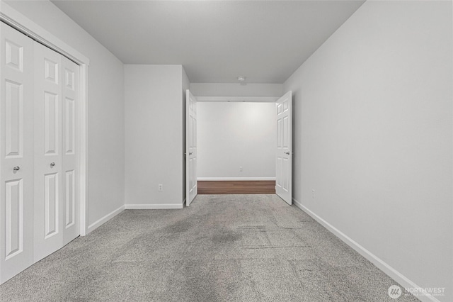 unfurnished bedroom with a closet, light carpet, and baseboards