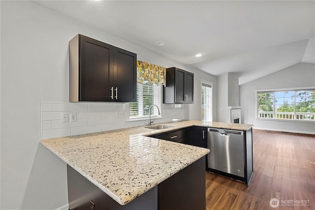 kitchen with backsplash, a sink, light stone countertops, dishwasher, and a peninsula