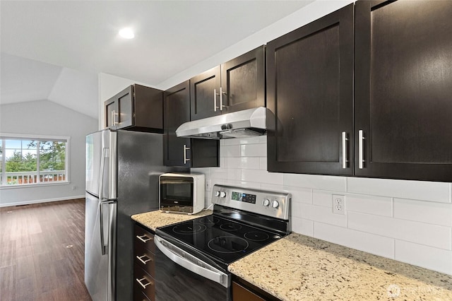 kitchen with appliances with stainless steel finishes, dark wood-type flooring, vaulted ceiling, light stone countertops, and under cabinet range hood