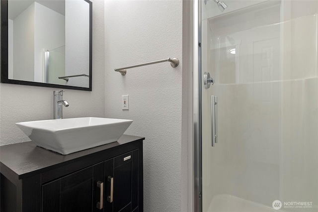 full bath with a shower stall, vanity, and a textured wall