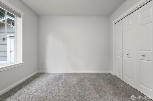 unfurnished bedroom with carpet floors, a closet, multiple windows, and baseboards