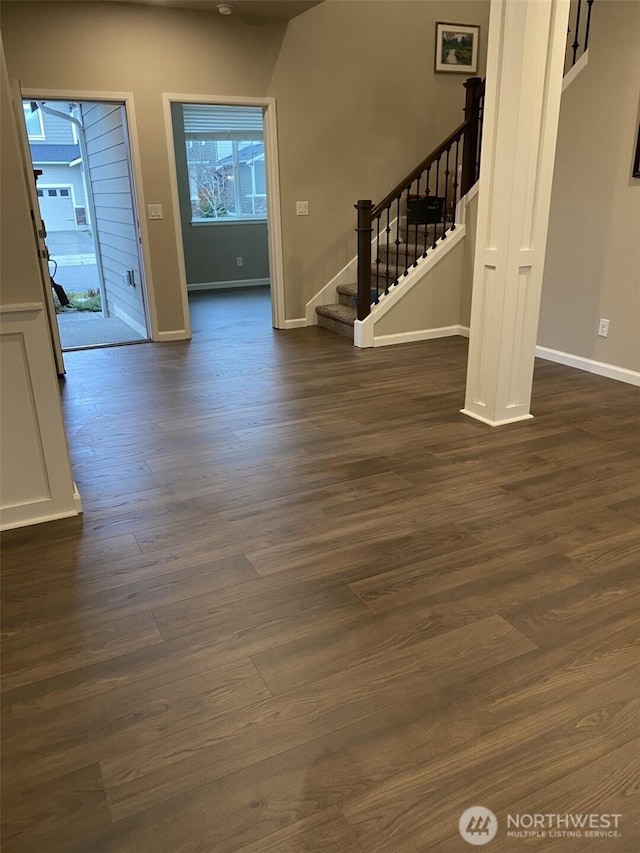 foyer entrance featuring dark wood-style floors, stairway, and baseboards