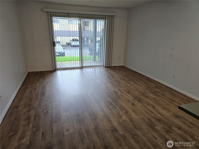 spare room featuring dark wood-type flooring and baseboards