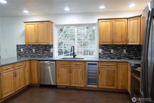 kitchen with wine cooler, stainless steel appliances, dark wood-type flooring, a sink, and dark countertops