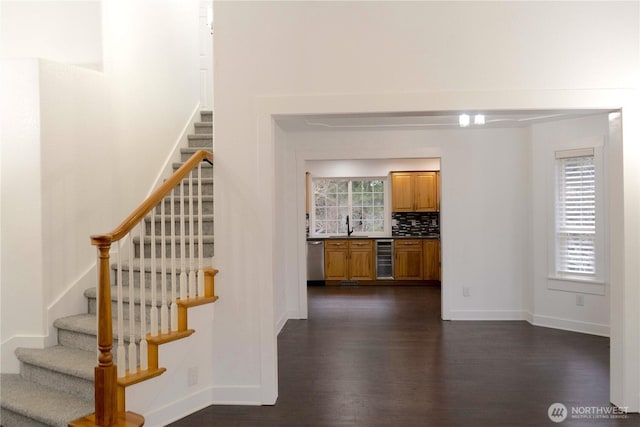 staircase featuring beverage cooler, baseboards, and wood finished floors