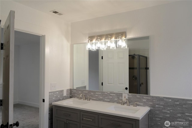 full bathroom with a stall shower, visible vents, a sink, and double vanity