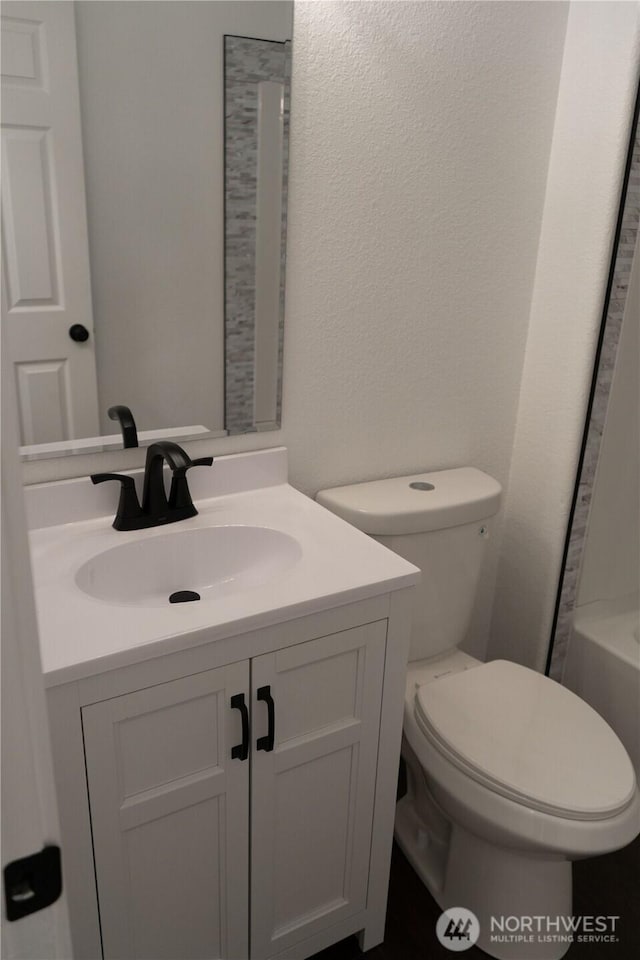 bathroom with vanity, toilet, and a bath