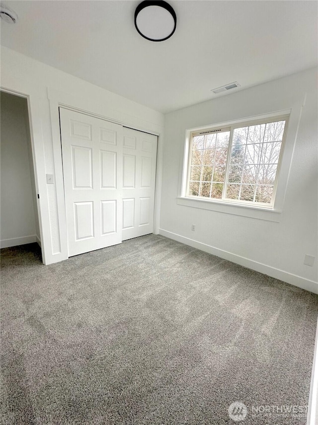 unfurnished bedroom featuring carpet, a closet, visible vents, and baseboards