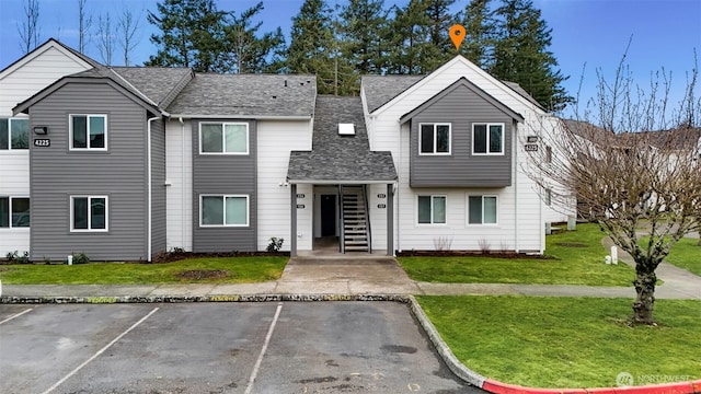 view of front facade with a front lawn, uncovered parking, and roof with shingles