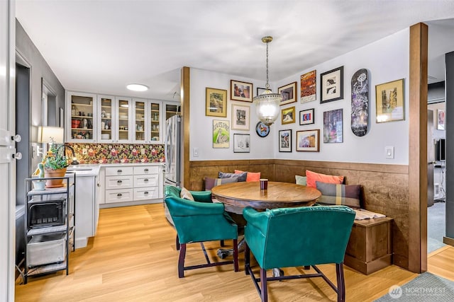 dining space with light wood-style floors, a wainscoted wall, and breakfast area