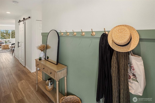 interior space featuring a barn door, wood finished floors, and baseboards