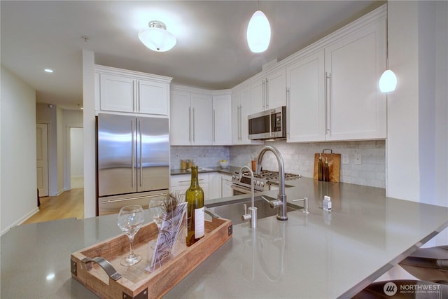 kitchen with a peninsula, white cabinetry, appliances with stainless steel finishes, and decorative backsplash