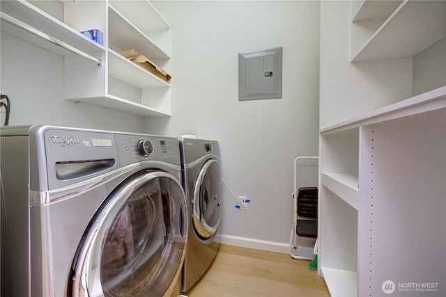 washroom with laundry area, electric panel, baseboards, wood finished floors, and separate washer and dryer