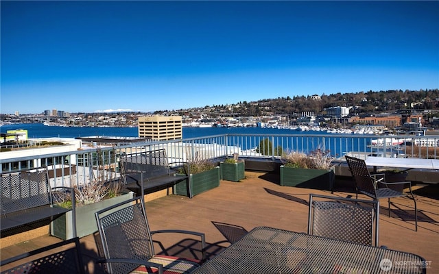 view of patio / terrace with a water view, a balcony, and outdoor dining space