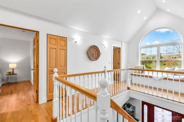 hallway with baseboards, light wood-type flooring, an upstairs landing, recessed lighting, and high vaulted ceiling