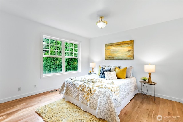 bedroom with visible vents, baseboards, and wood finished floors