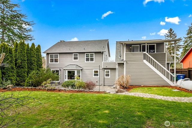 back of property featuring a yard, fence, and stairway