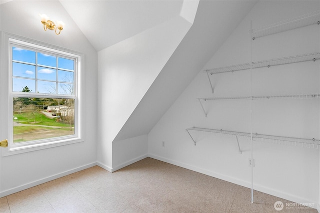 interior space with baseboards, lofted ceiling, and light floors