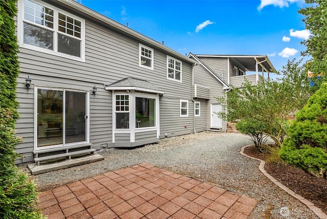 rear view of house featuring a patio area, gravel driveway, and entry steps