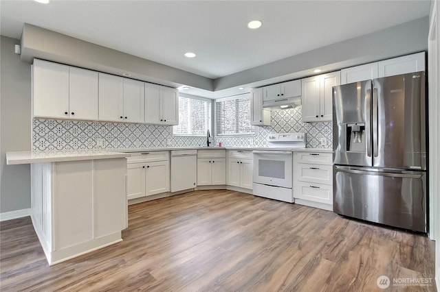 kitchen with white appliances, light countertops, under cabinet range hood, and white cabinetry