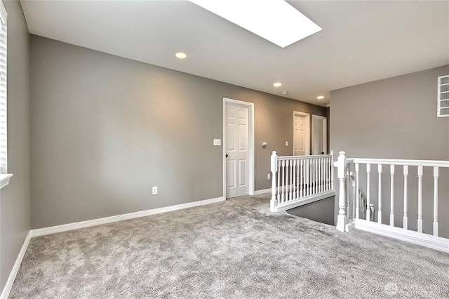 spare room with a skylight, carpet flooring, baseboards, and recessed lighting