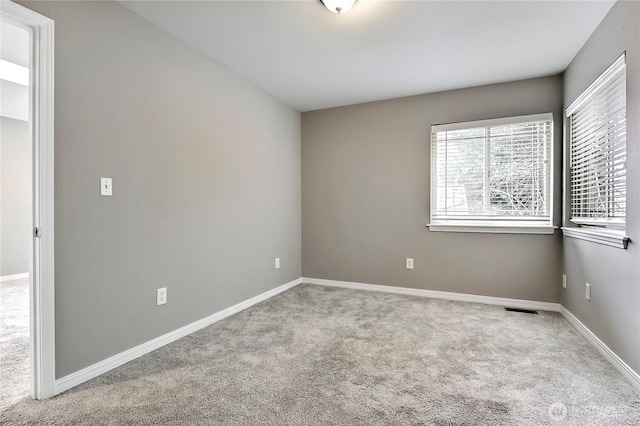 unfurnished room with visible vents, baseboards, and light colored carpet