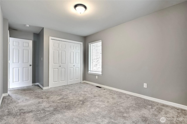 unfurnished bedroom featuring baseboards, a closet, and light colored carpet