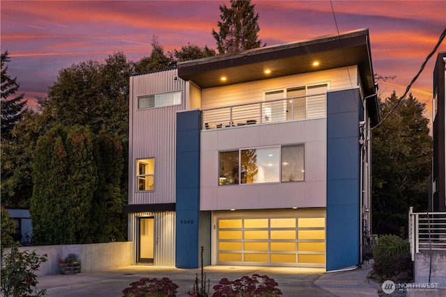 modern home with a garage, concrete driveway, and a balcony