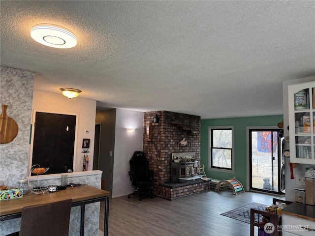 living room with a textured ceiling, wood finished floors, and a wood stove