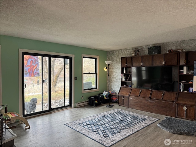 living area with light wood-style flooring, baseboard heating, and a textured ceiling