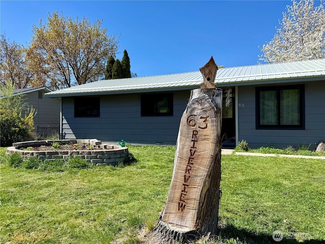 ranch-style house with a garden, metal roof, and a front lawn