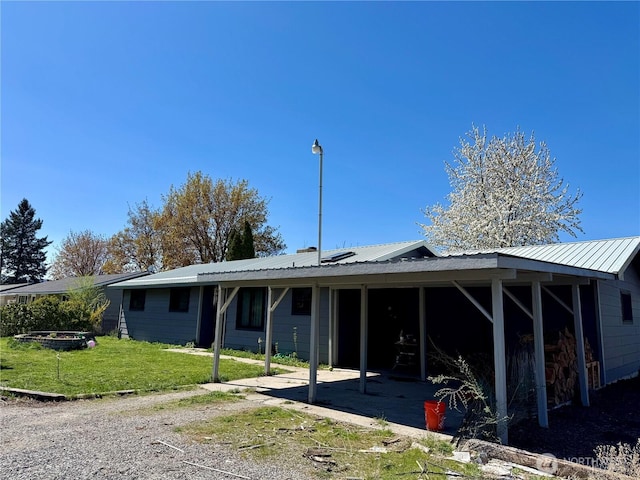 rear view of house with a patio area, metal roof, and a yard