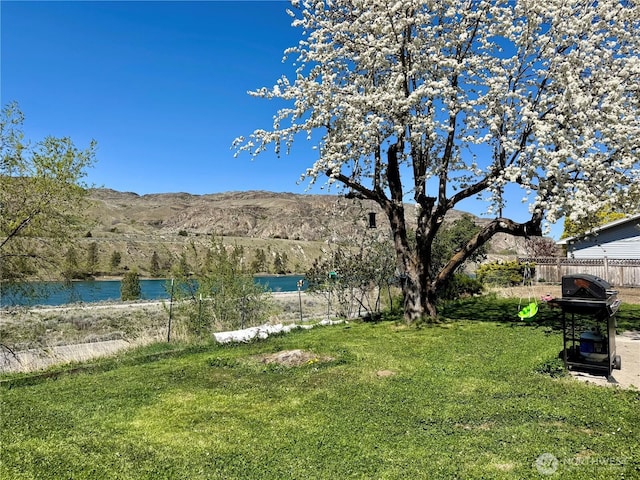 view of yard with a water and mountain view and fence