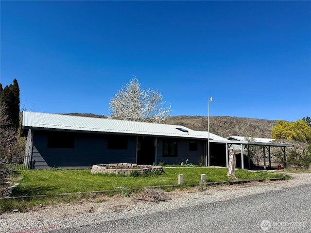 view of front facade with a mountain view, a carport, metal roof, and a front yard