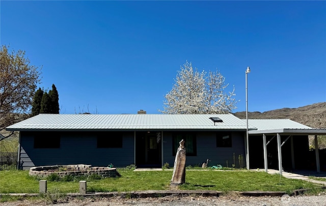 view of front of home featuring a front lawn, metal roof, and a chimney