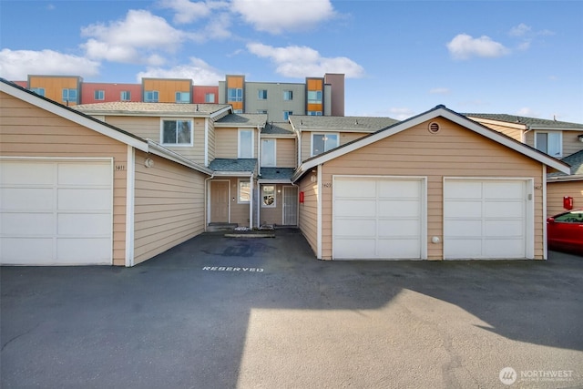 view of property with a garage and a shingled roof