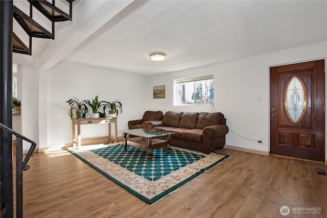 living room with a textured ceiling, baseboards, and wood finished floors