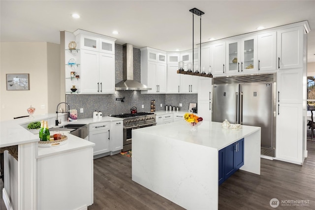 kitchen featuring wall chimney exhaust hood, glass insert cabinets, light countertops, and premium appliances