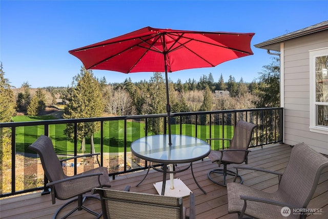 wooden deck with outdoor dining space and a lawn